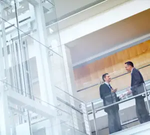 Two men in suits talking on a balcony.