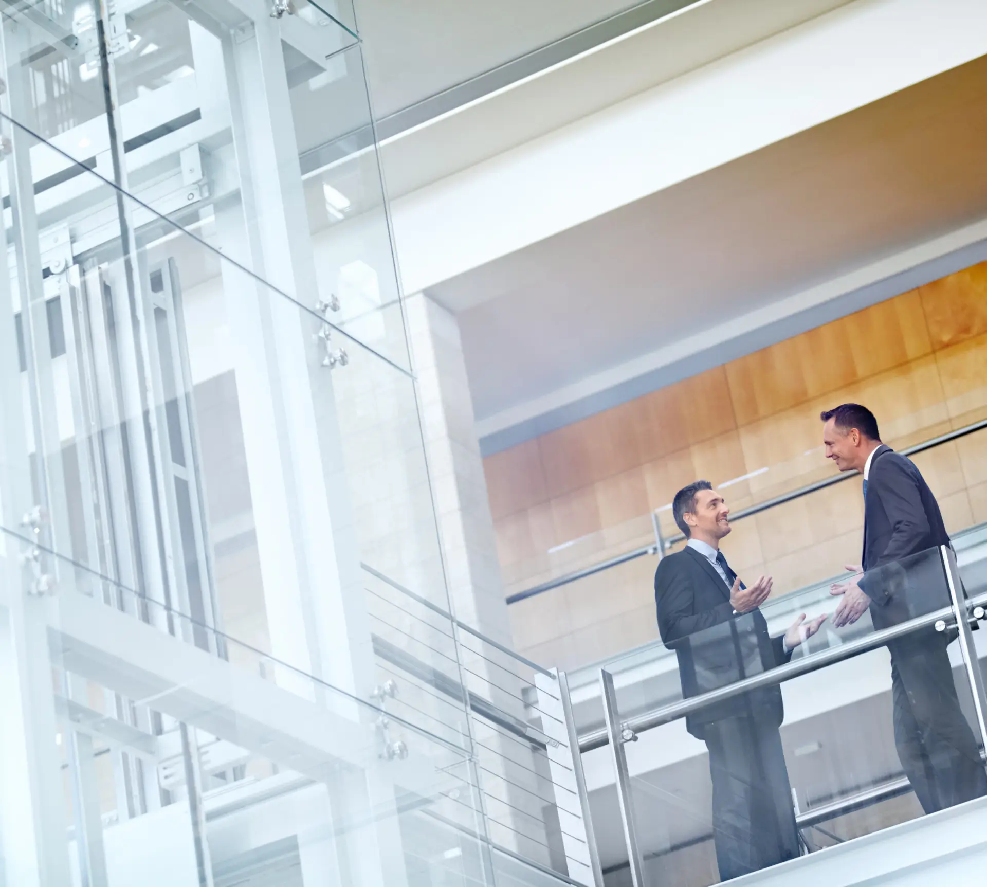 Two men in suits talking on a balcony.